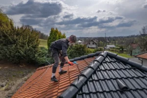Mycie dachu z dachówki przez pracownika w Warszawie